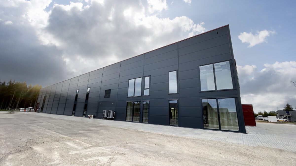 Industribygning fra Hallgruppen i stål og glas med lyse belægningssten foran.